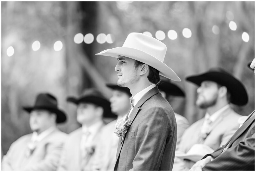 Black and white image of groom in cowboy hat waiting for bride at altar | Coosada Alabama Wedding Photographer Amanda Horne