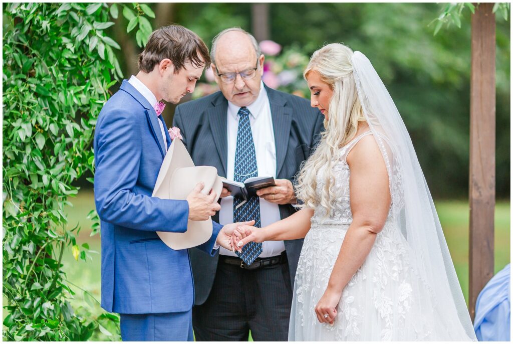 Bride and groom holding cowboy hat pray during ceremony | Coosada Alabama Wedding Photographer Amanda Horne 