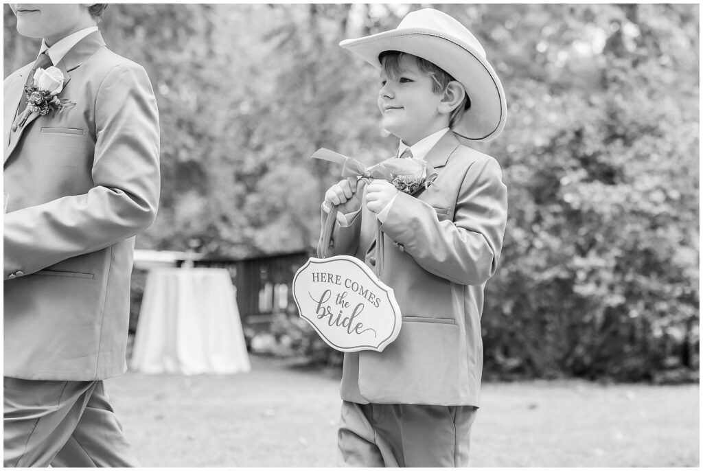 Black and white image of ringbearer carrying "here comes the bride" sign | Coosada Alabama Wedding Photographer Amanda Horne