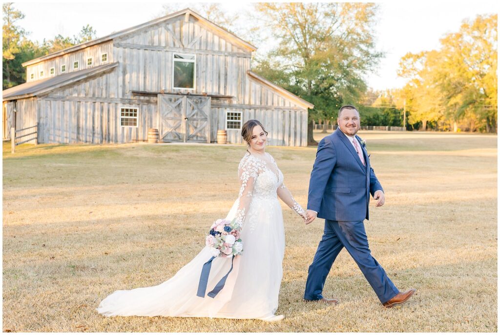 Bride and Groom walking in front of barn at the Farm at Lullwater. | Alabama Wedding Photographer Amanda Horne