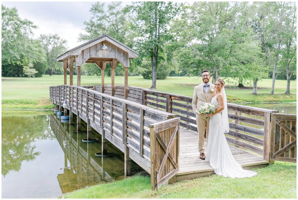 Bride and groom posed portrait by the bridge at the Farm at Lullwater