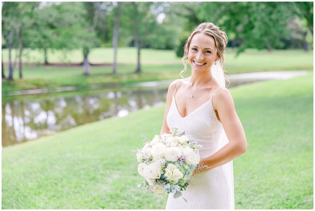 Bride with her bouquet near the water at the venue